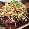 STAKE YOUR CLAIM: The ginger ponzu ribeye steak comes with a load of sriracha-laced onion strings. Photo by Ngoc Ngo