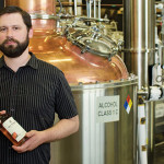 BEST SHOT: Brand ambassador Ryan Hummel stands with a bottle of 10th St. Distillery’s flagship product: an aged, peated whiskey. Photo by John Dyke